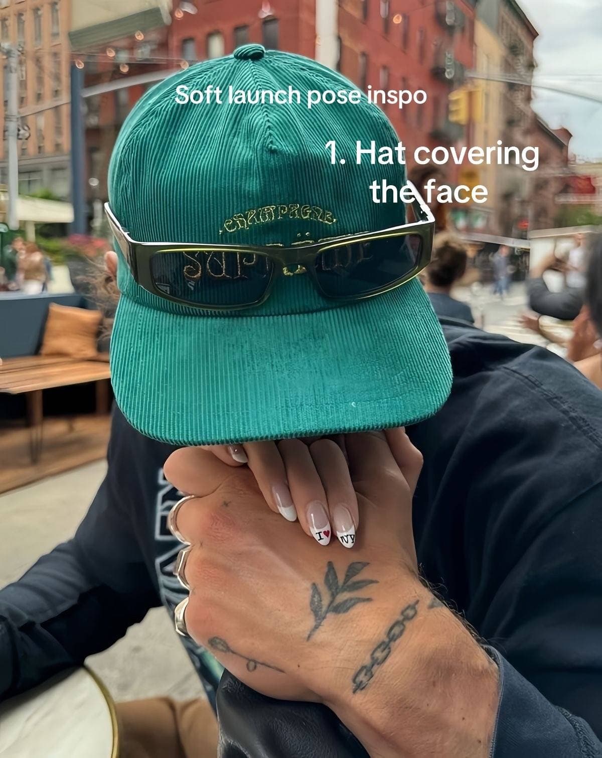 A person hiding their face behind a green cap while holding a partner's hand; the overlay labels it soft-launch pose inspiration.