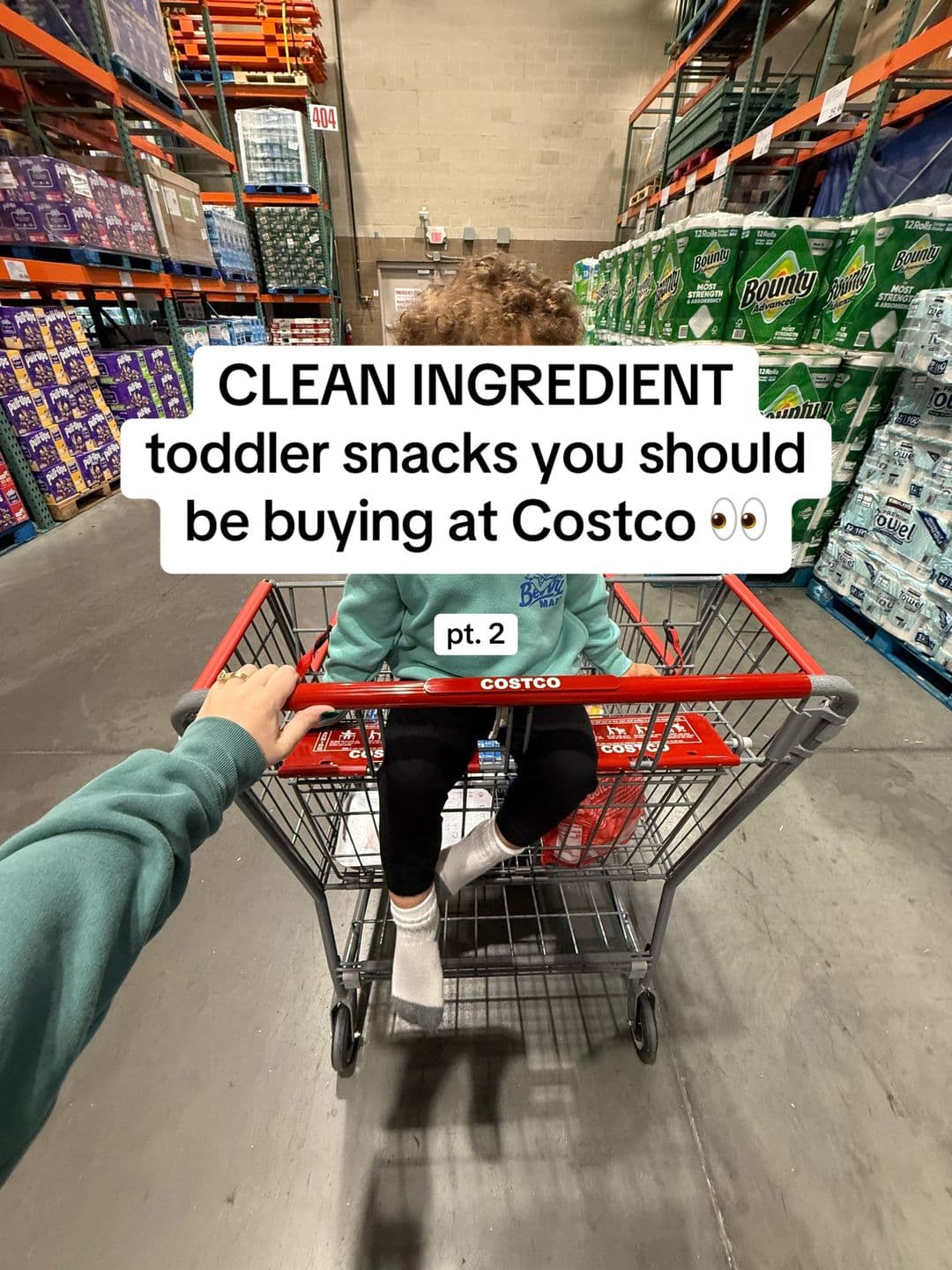 The first slide of the Costco post, showing a child in a cart in a warehouse aisle under text promising clean-ingredient toddler snacks.