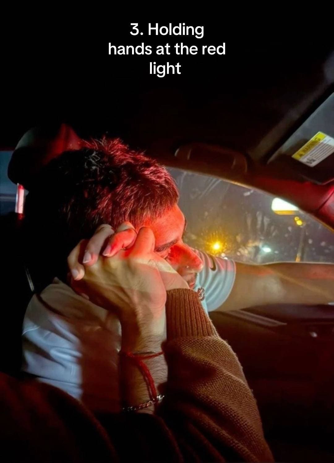 A couple holding hands in a car under red light with an overlay about holding hands at a red light.