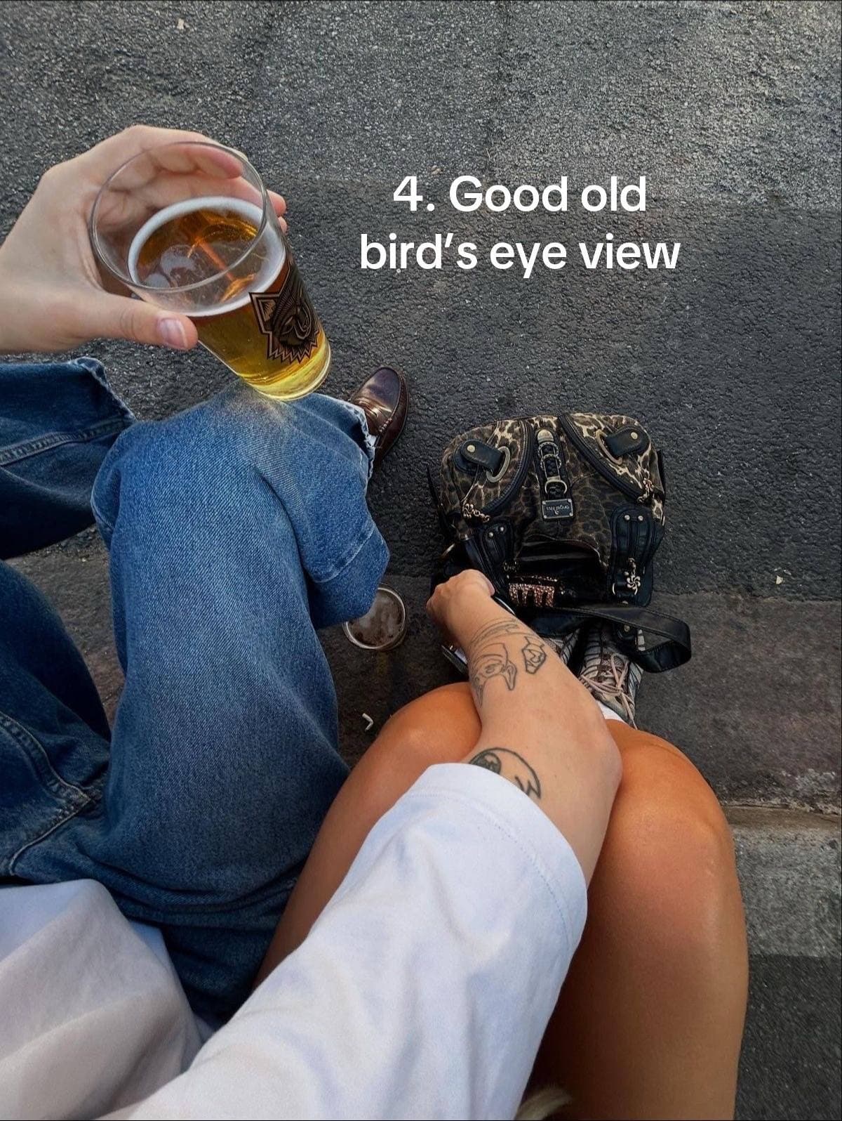 A top-down view of a seated couple, including a hand holding a drink.