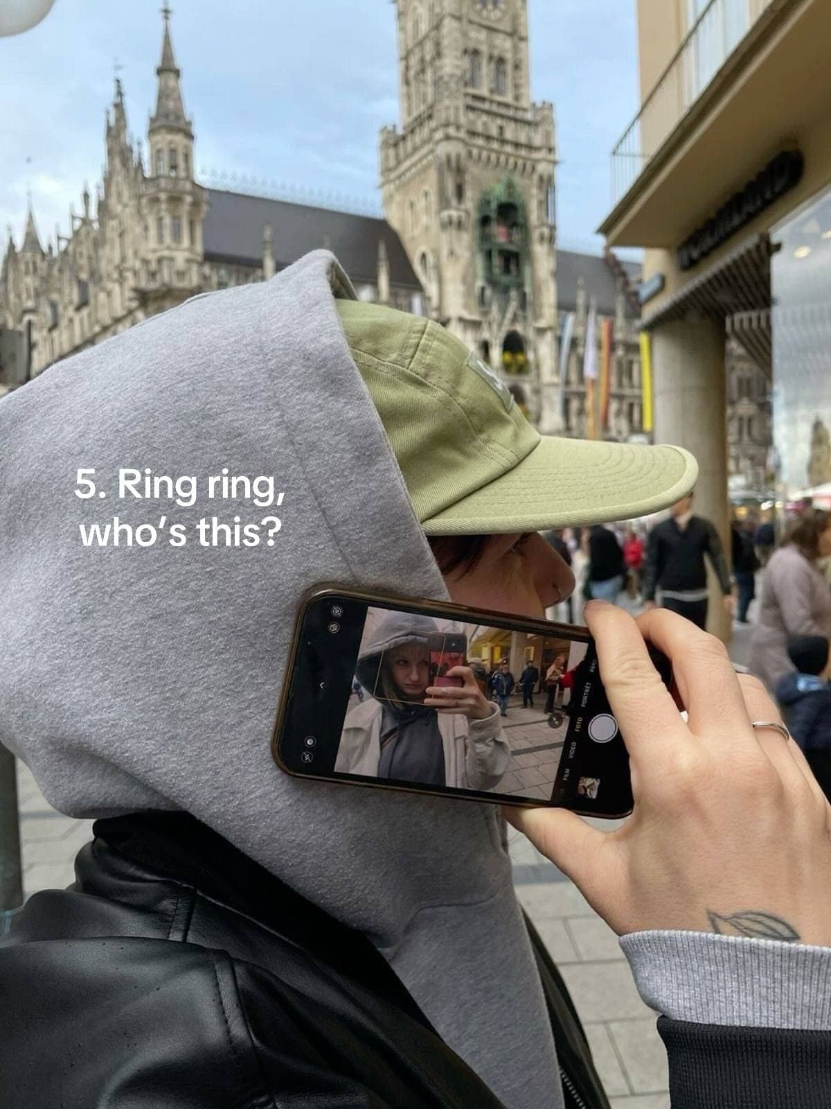 One person photographing another through a phone screen on a city street.